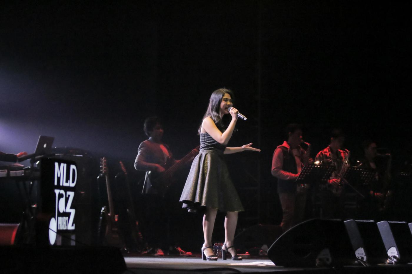 Kiara Riz menggunakan dress dan sepatu berwana hitam di atas panggung